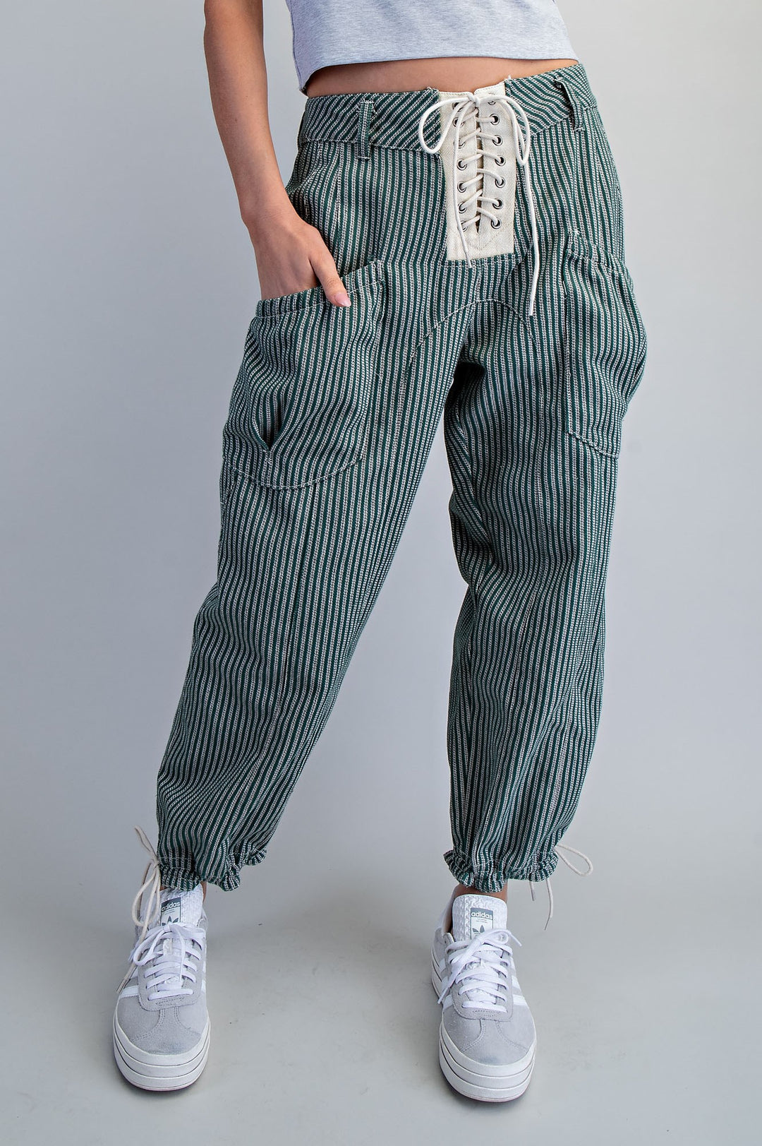 Woman wearing stripe green pants on plain background