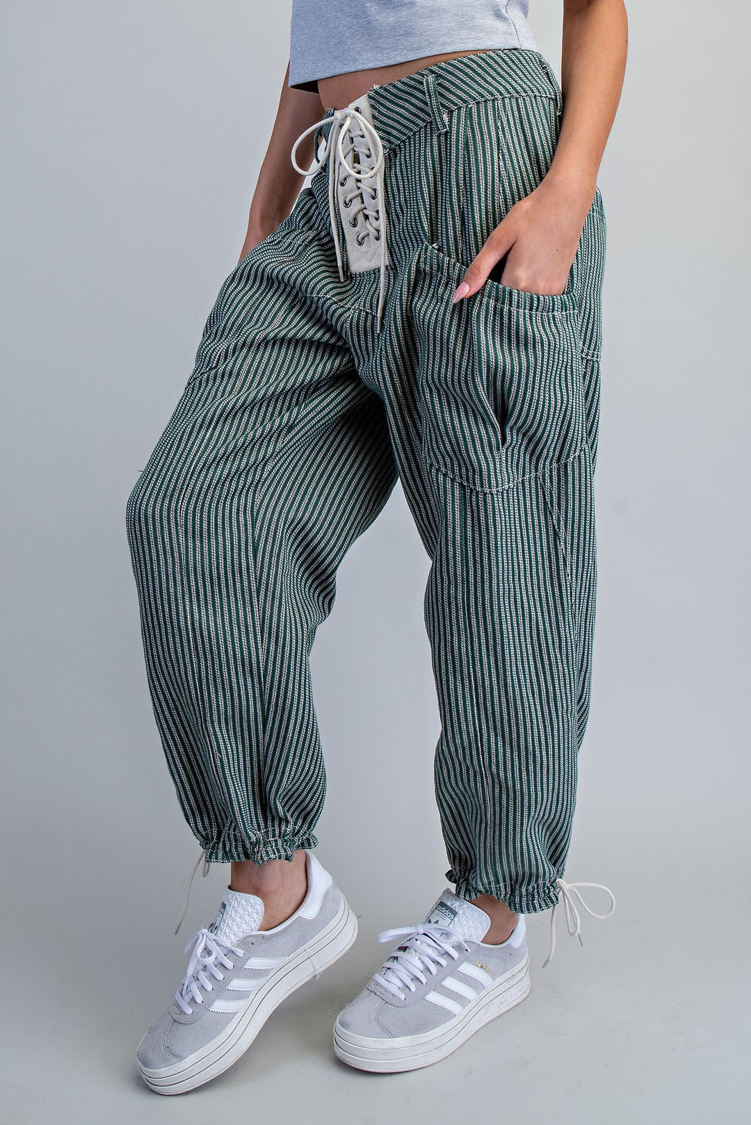 Woman wearing stripe green pants on plain background