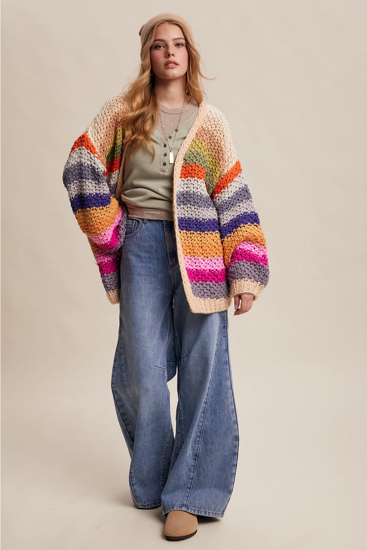 Woman wearing a colorful striped cardigan and blue jeans on a beige background