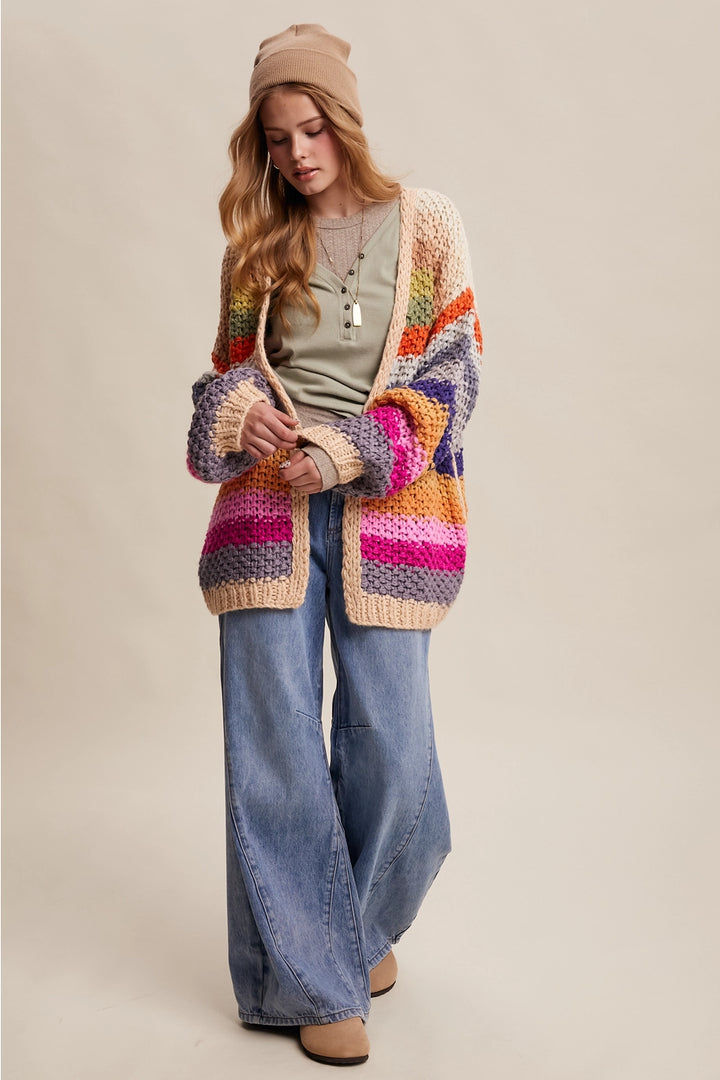 Woman wearing a colorful striped cardigan and jeans on a beige background