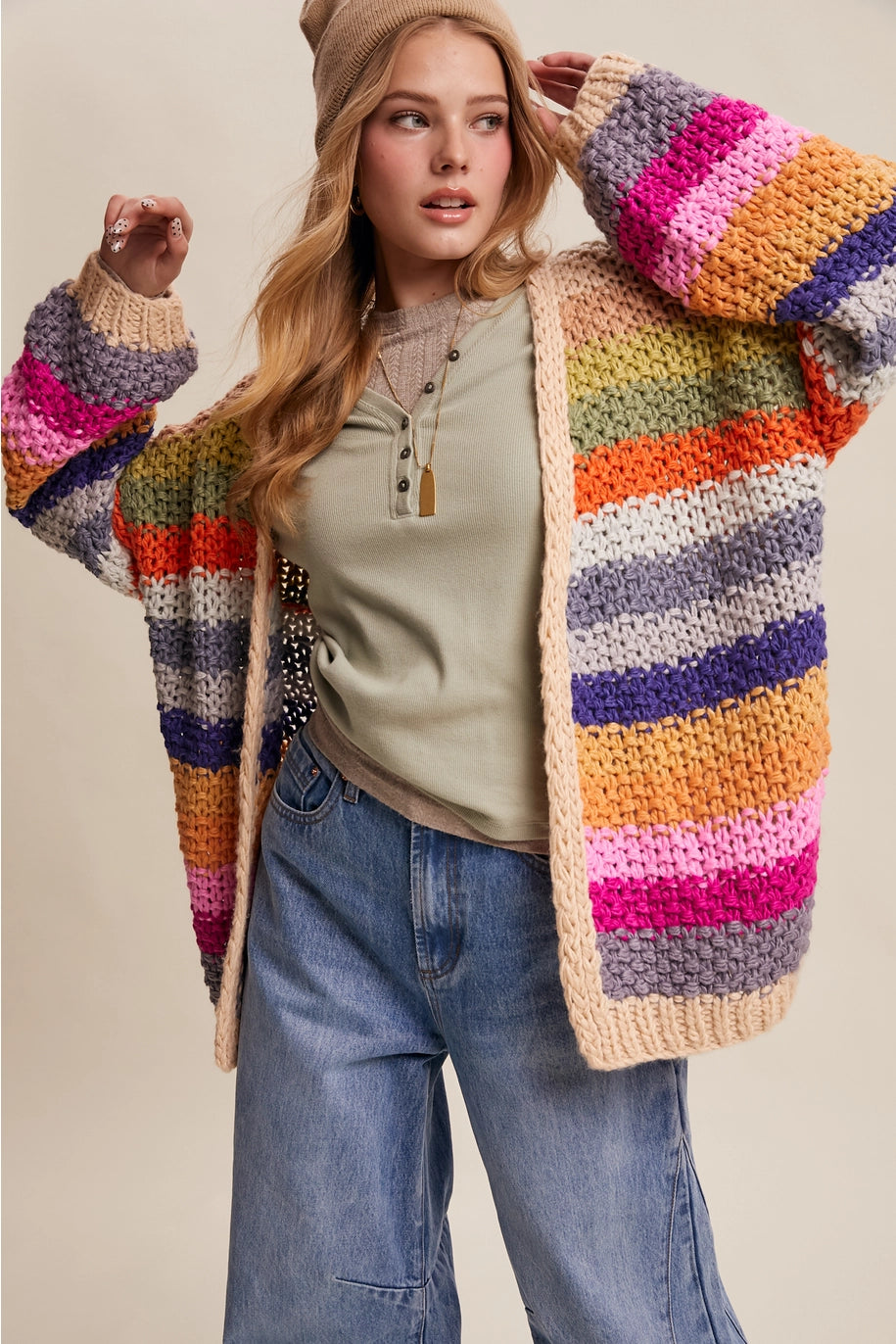 Woman wearing a colorful striped cardigan against a neutral background