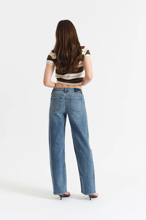 Person wearing a striped shirt and blue jeans on a white background