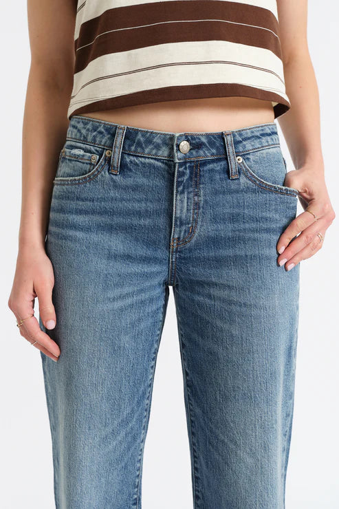 Person wearing blue jeans and a striped top on a white background