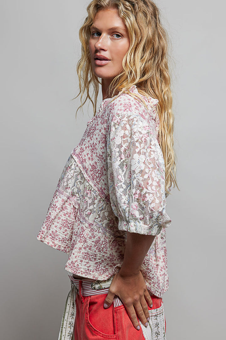 Woman wearing a floral blouse and red pants against a gray background