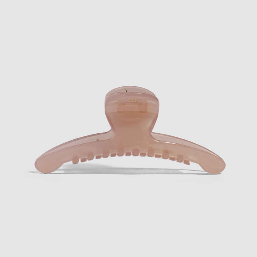 A translucent blush pink hair claw clip shown from the front on a light gray background.