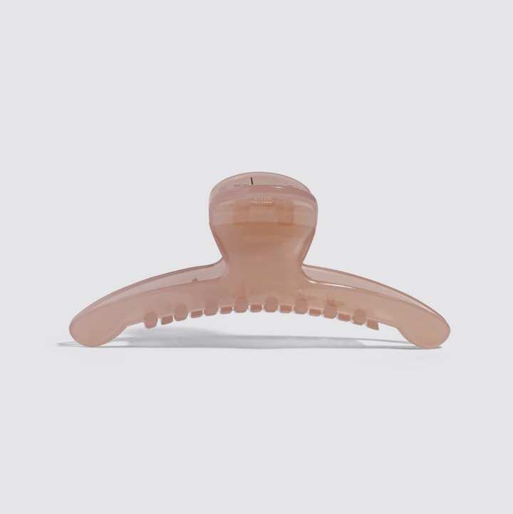 A translucent blush pink hair claw clip shown from the front on a light gray background.