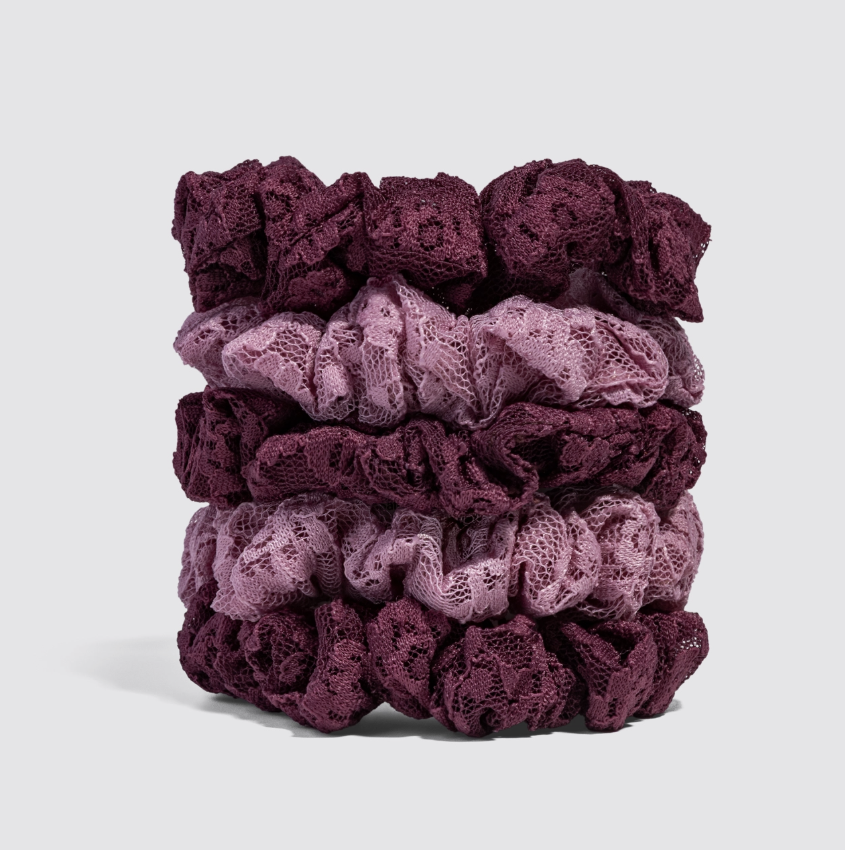 A stack of five knotted lace hair scrunchies in shades of deep burgundy and dusty mauve, photographed on a clean light gray background.