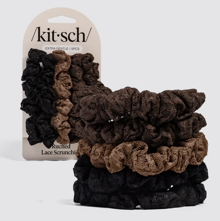 A set of five knotted lace scrunchies in black, brown, and taupe, displayed in front of their original cardboard packaging card on a light gray background.