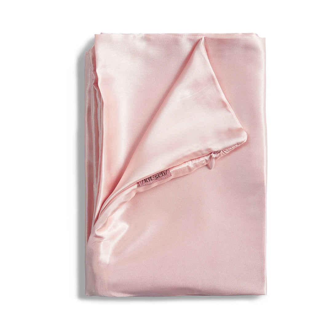 Blush satin pillowcase folded on plain background