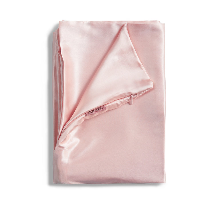 Blush satin pillowcase folded on plain background