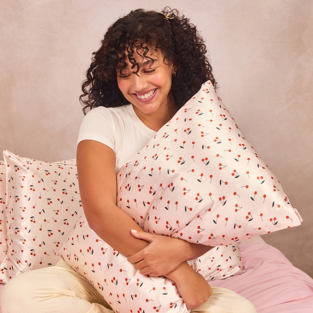 Woman holding pillow with satin pillowcase with cherries on it