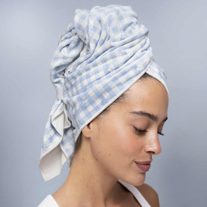 Woman wearing blue gingham towel on her head on plain background