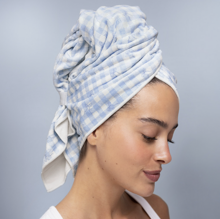 Woman wearing blue gingham towel on her head on plain background