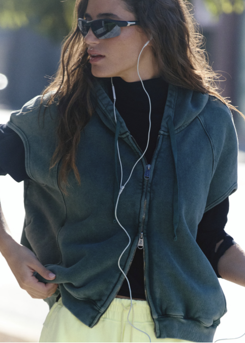 Woman wearing lime green shorts with dark green vest outdoors