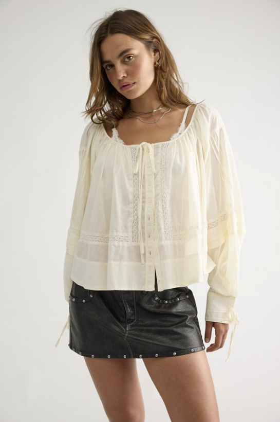 Woman wearing beige lace top and black skirt on white skirt
