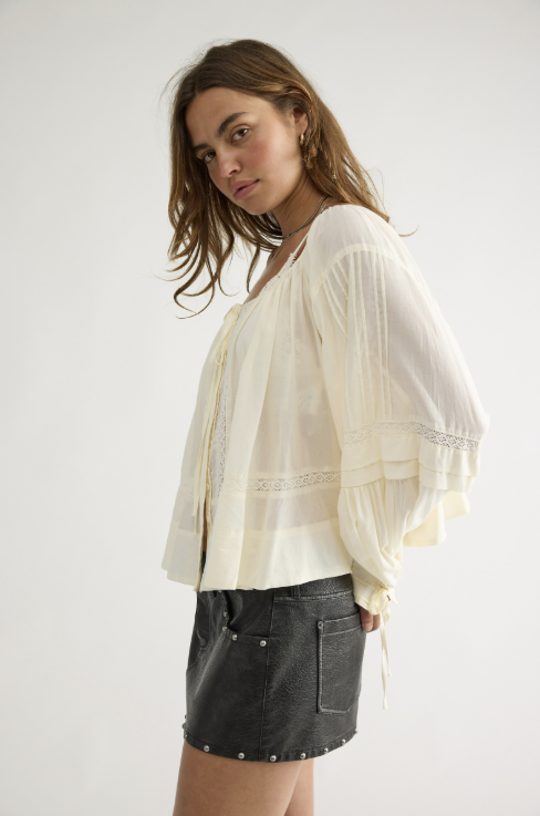 Woman wearing beige lace top and black skirt on white background