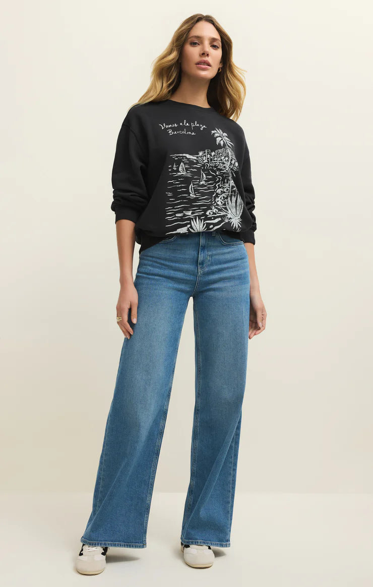 Woman wearing a black graphic sweatshirt and blue jeans on a white background