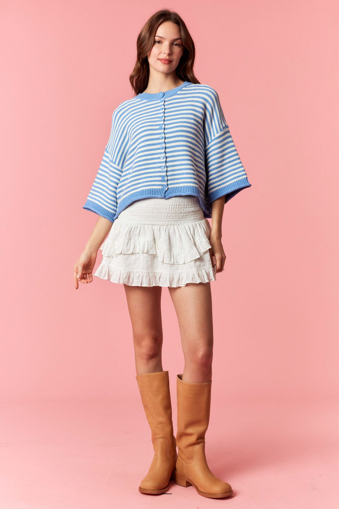 Woman wearing blue and white stripe short sleeve cardigan and white mini skirt on plain background