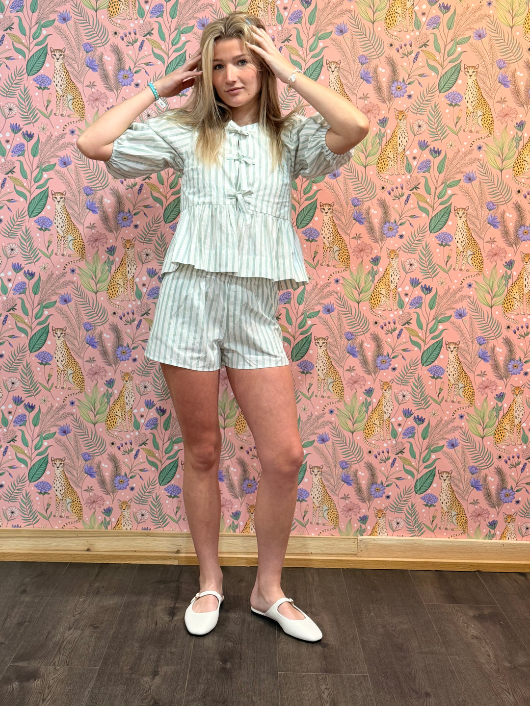 Woman wearing matching green and white stripe set on floral background