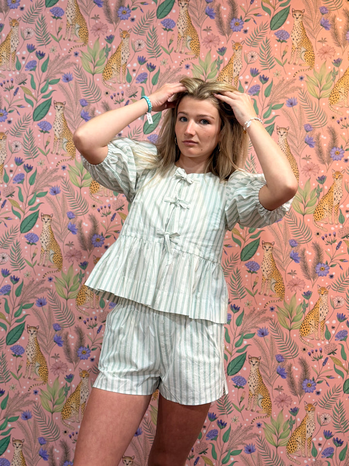 Woman posing in a layered outfit against a pink wallpaper with animal prints
