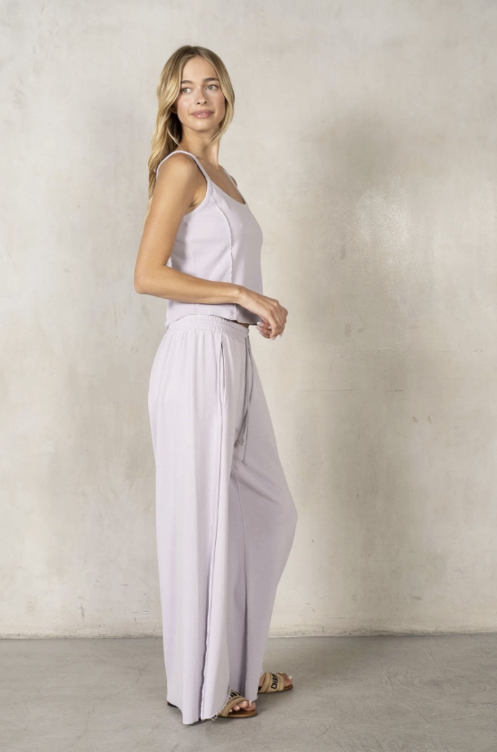 Woman wearing a light purple jumpsuit against a plain background