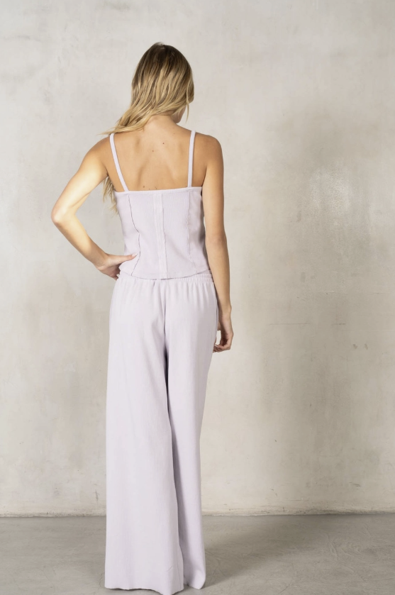 Woman wearing a light purple jumpsuit against a plain background