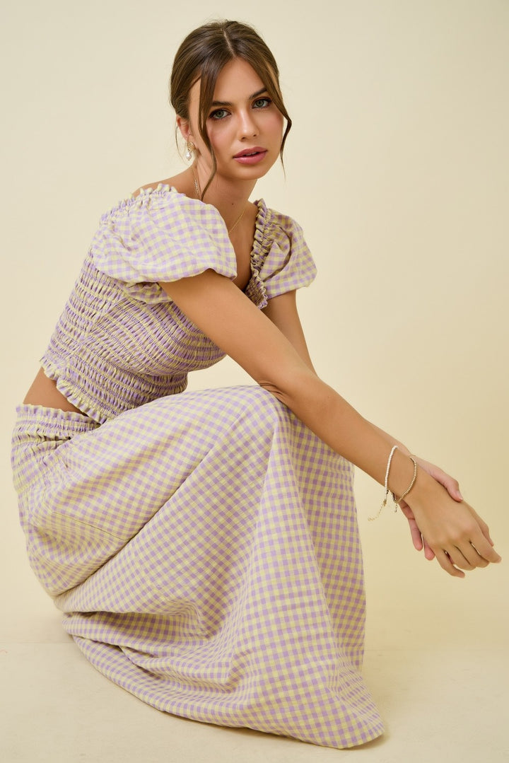 Woman wearing a checkered outfit sitting on a beige background