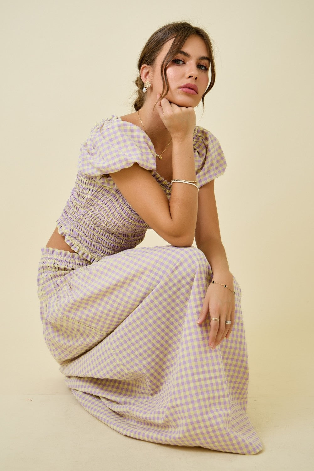Woman wearing a patterned outfit sitting on a beige background