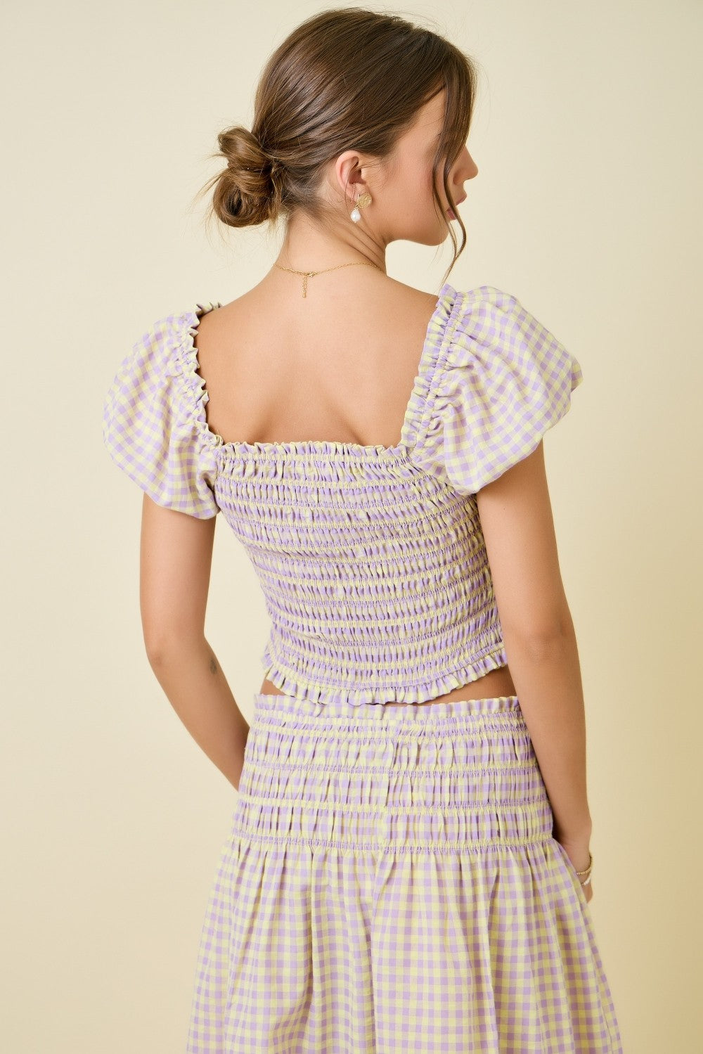 Woman wearing a checkered dress with a beige background