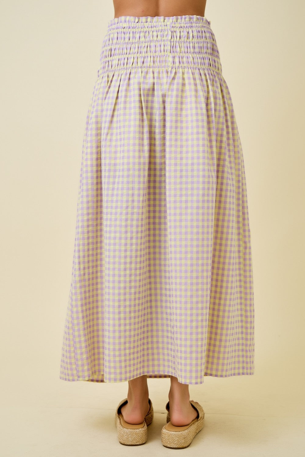 Person wearing a checkered skirt on a beige background