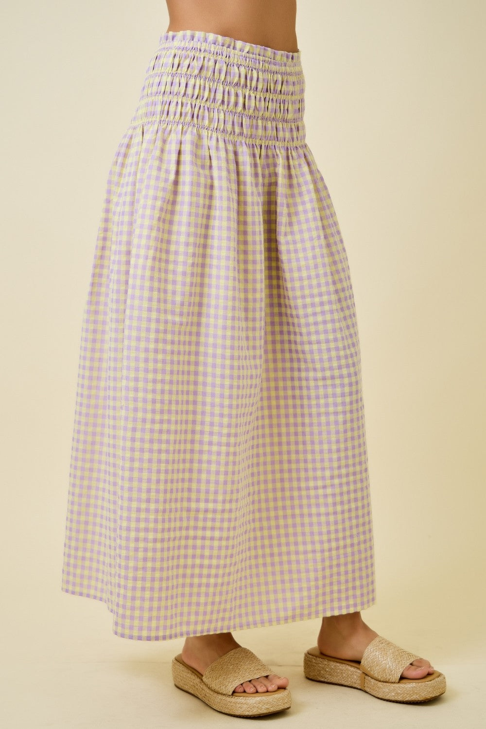 Person wearing a long checkered skirt on a beige background