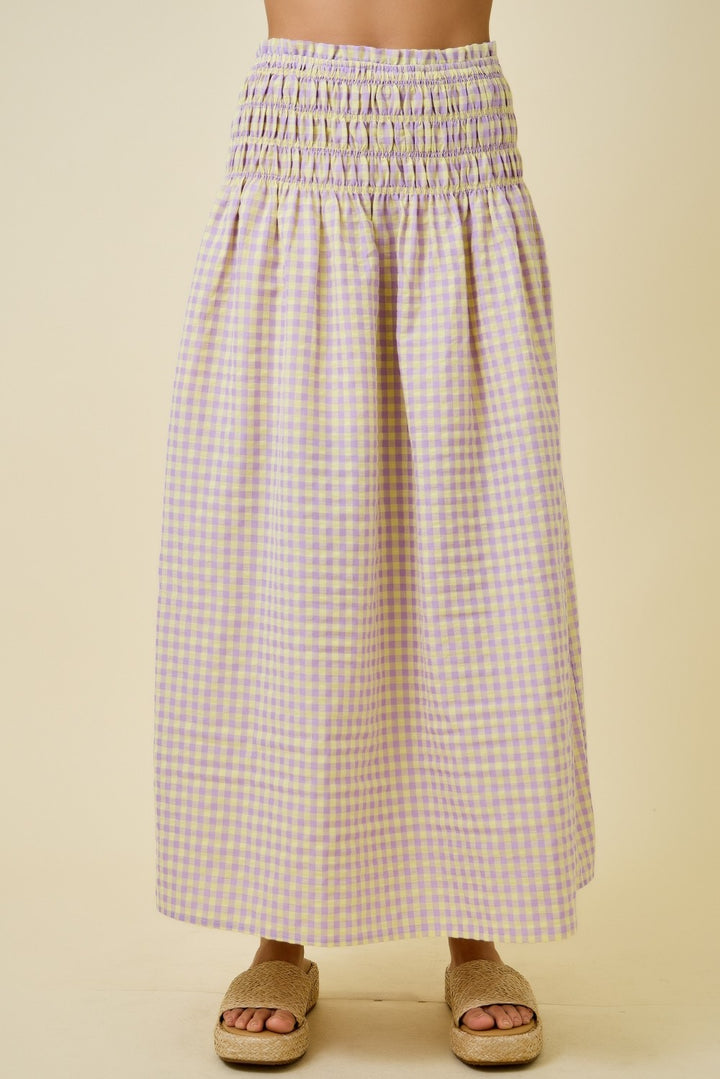 Person wearing a long, checkered skirt on a beige background