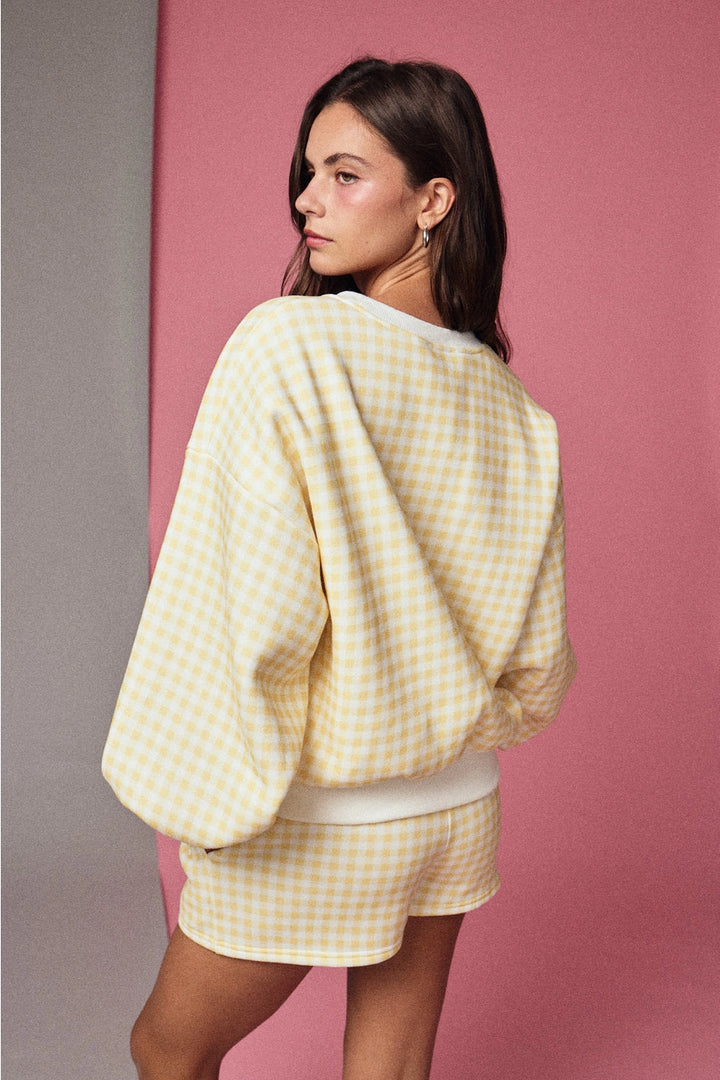 Woman wearing a yellow checkered outfit against a pink background