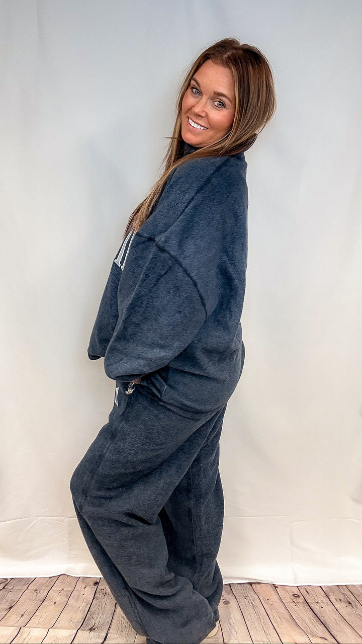 Woman wearing matching navy sweatsuit shown from side on white background