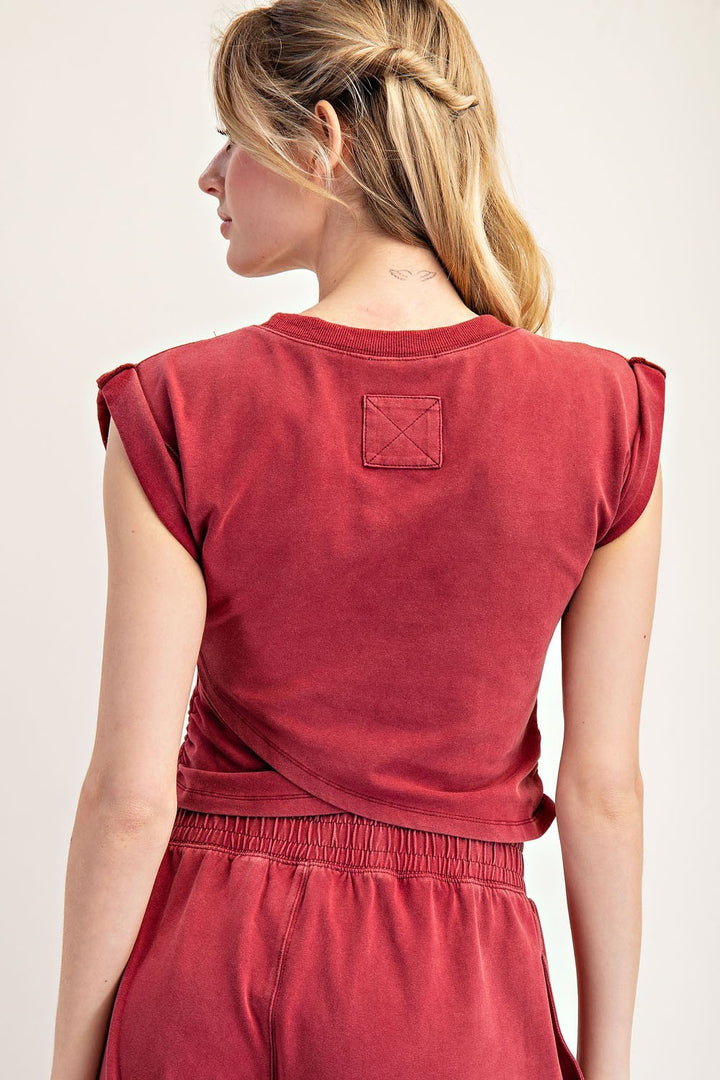 Woman wearing a red sleeveless top and pants on a plain background