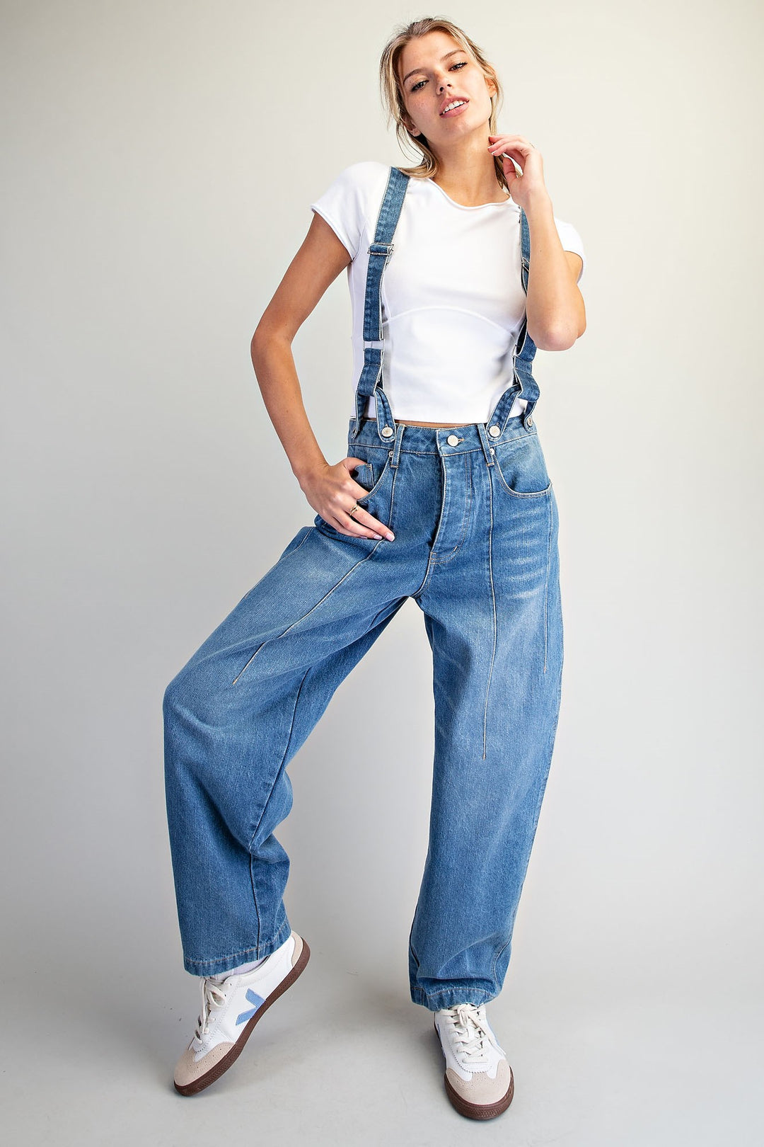 Woman wearing denim overalls on plain background
