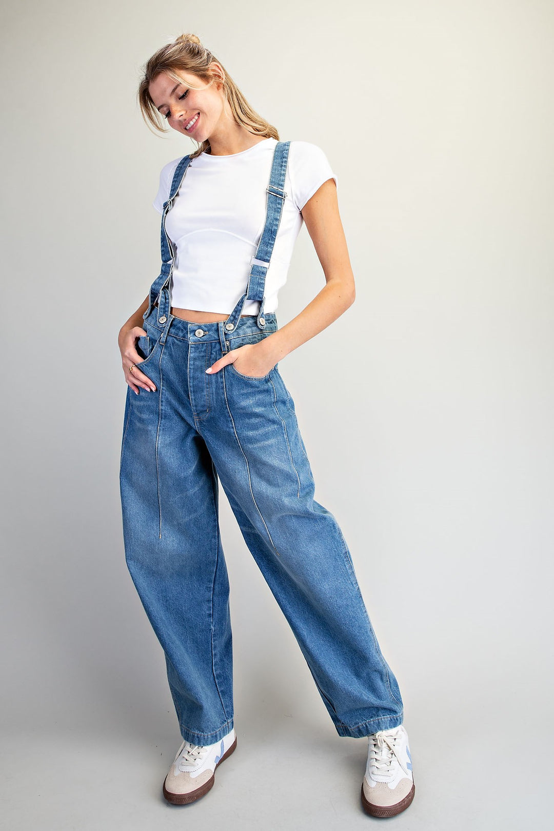 Woman wearing denim overalls on plain background