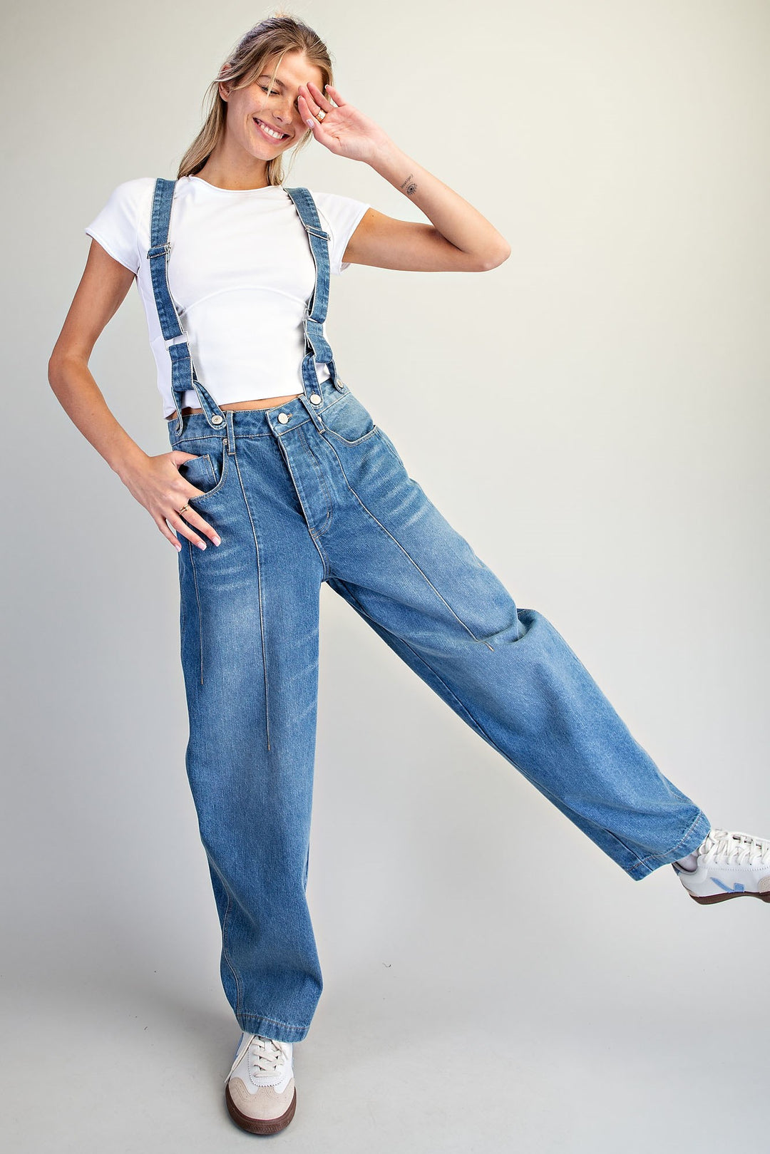 Woman wearing denim overalls on plain background