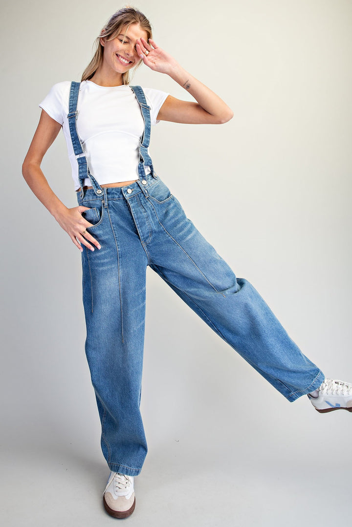 Woman wearing denim overalls on plain background
