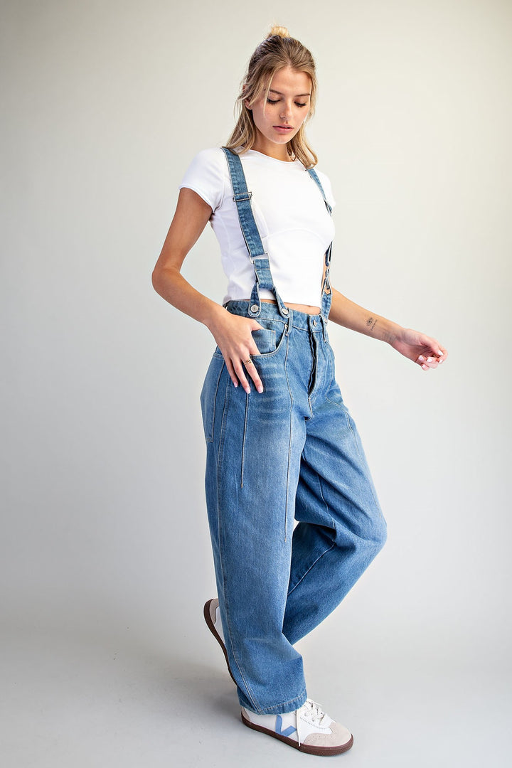 Woman wearing denim overalls on plain background