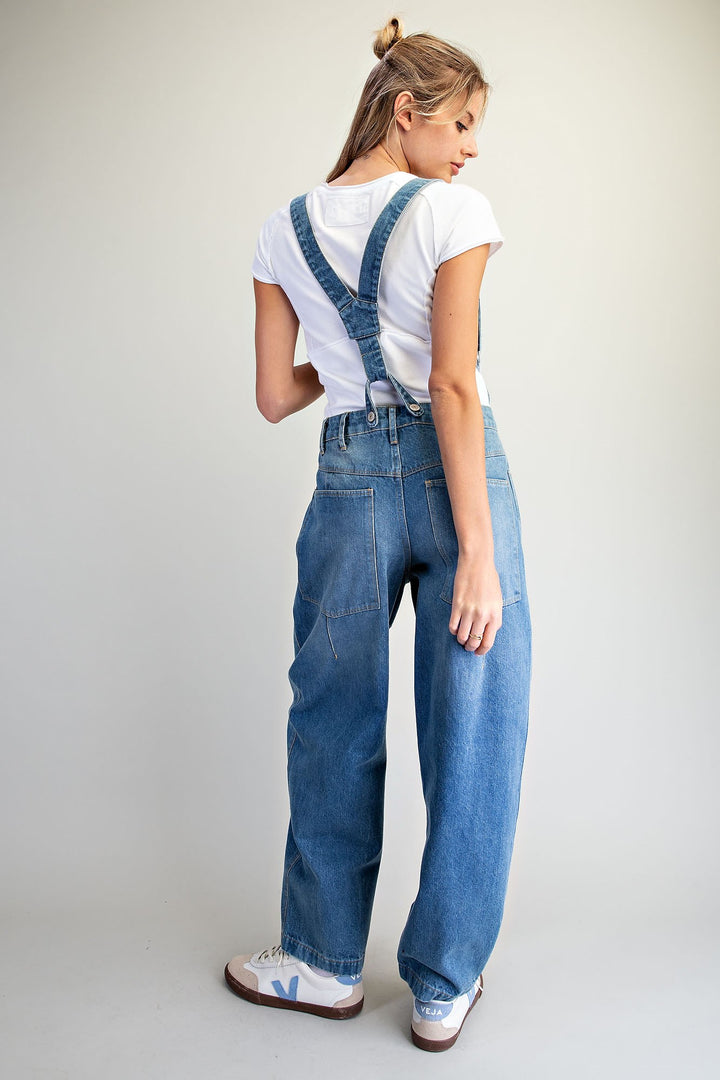 Woman wearing denim overalls on plain background