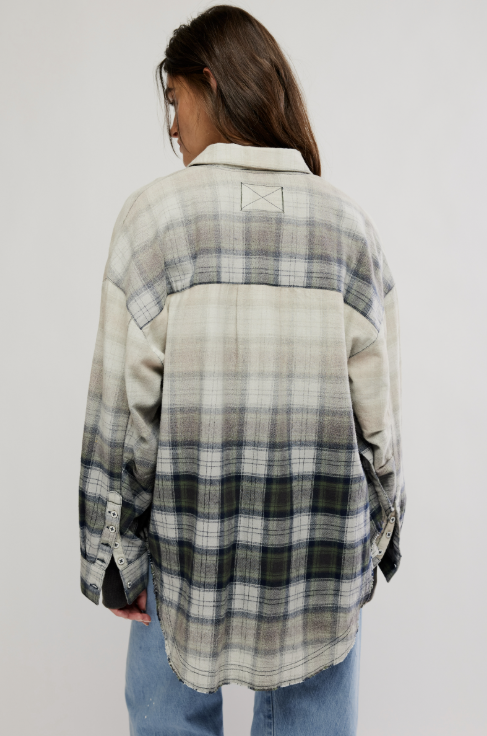 Woman shown from behind wearing ombre flannel and jeans on plain background
