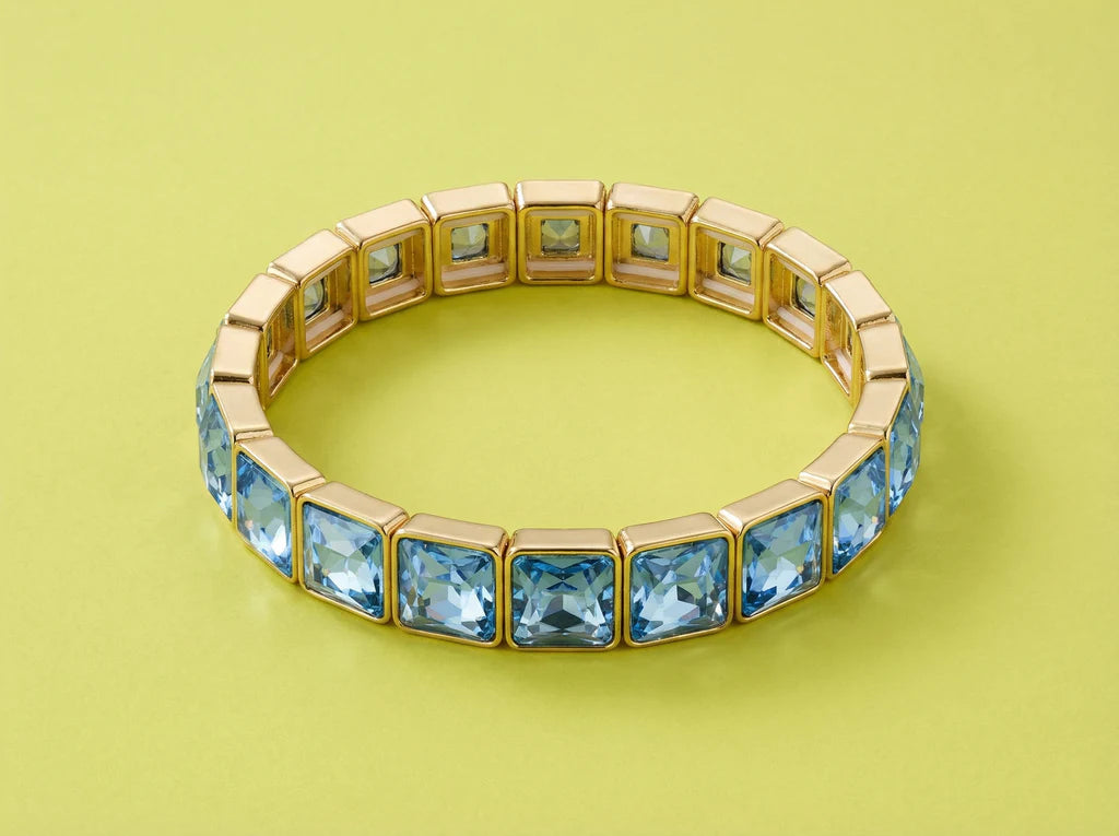 Gold bracelet with blue gemstones on a green background