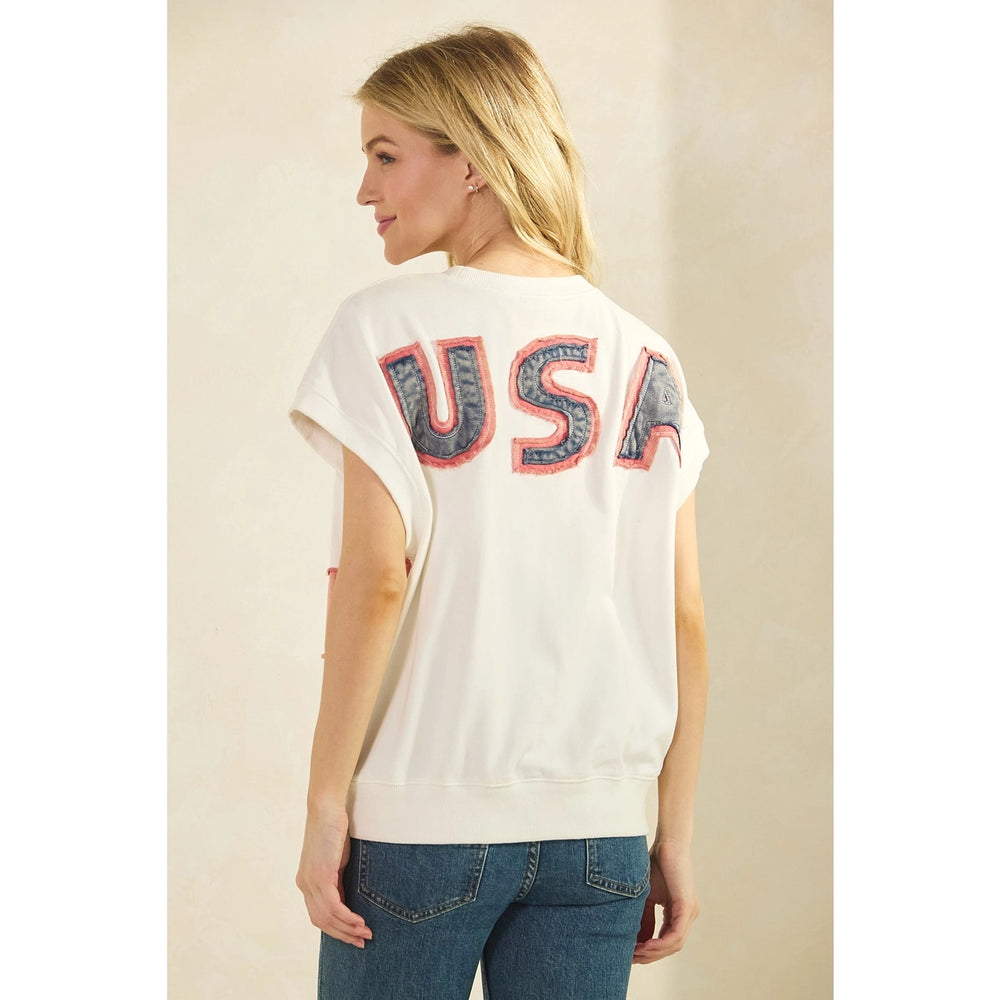 Woman wearing a white t-shirt with 'USA' printed on the back against a beige background