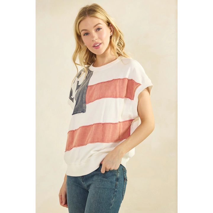 Woman wearing a white t-shirt with red and blue horizontal stripes and blue jeans on a beige background