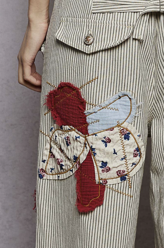 Close-up of a person wearing a striped garment with a decorative patch featuring a butterfly design.