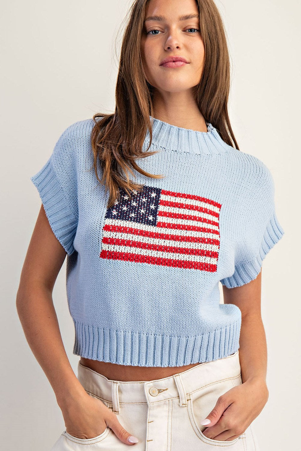 Light blue sweater with American flag design worn by a person on a plain background