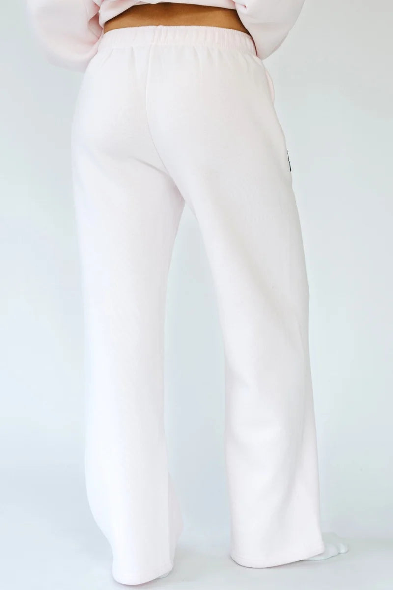 Woman shown from back wearing light pink sweatpants on white background