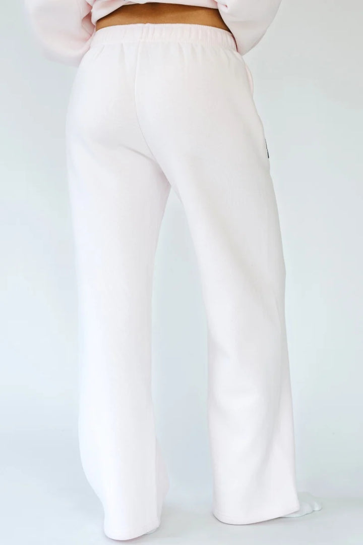 Woman shown from back wearing light pink sweatpants on white background
