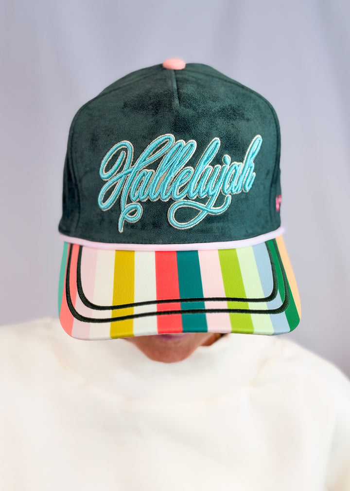 Woman wearing dark green suede trucker hat with striped bill and &